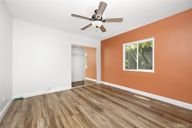 unfurnished bedroom featuring ceiling fan, a closet, and hardwood / wood-style flooring