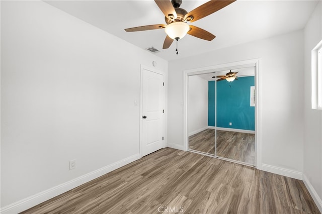 unfurnished bedroom featuring wood-type flooring, a closet, and ceiling fan