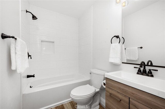 full bathroom featuring wood-type flooring, vanity, toilet, and tiled shower / bath combo