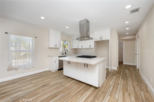 kitchen with island exhaust hood, a center island, white cabinets, and a wealth of natural light