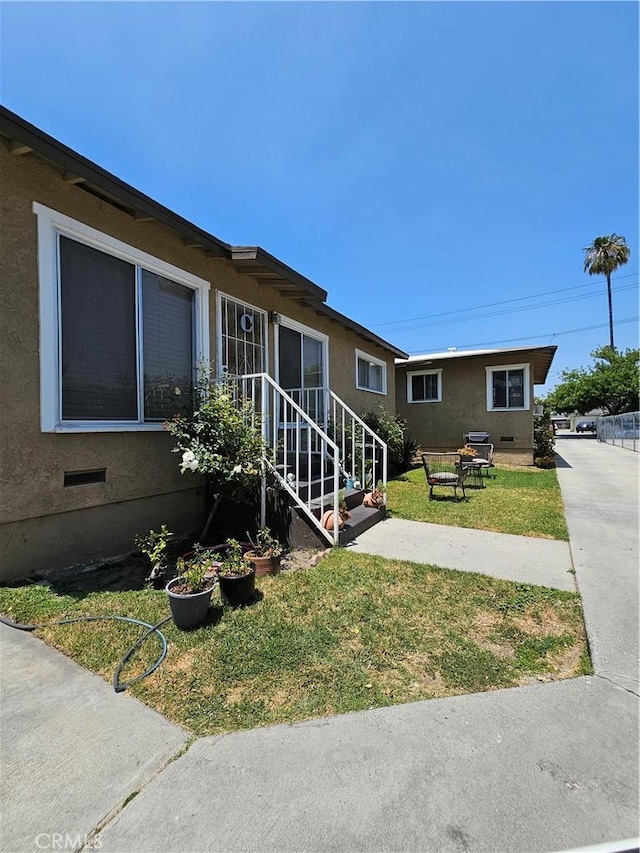 214 E Johnson St, Compton, CA 90220 - view of home's exterior with a lawn, crawl space, and stucco siding