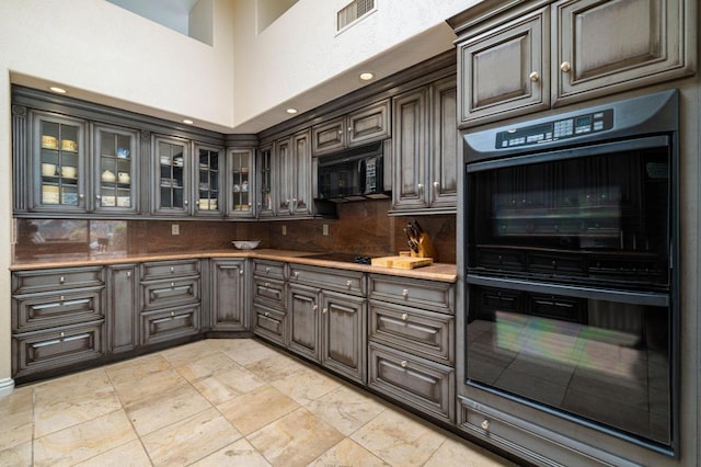 kitchen featuring black appliances, dark brown cabinets, tasteful backsplash, and a high ceiling