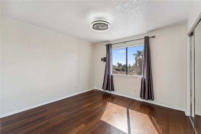 unfurnished room featuring a textured ceiling and dark hardwood / wood-style floors