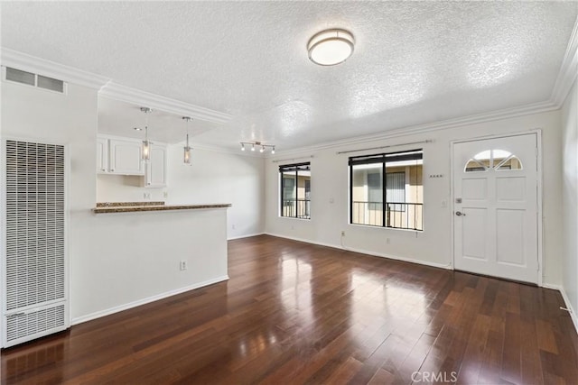 unfurnished living room with a textured ceiling, dark hardwood / wood-style floors, and ornamental molding