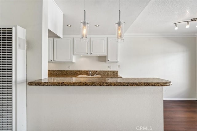 kitchen with kitchen peninsula, dark hardwood / wood-style flooring, sink, white cabinetry, and hanging light fixtures