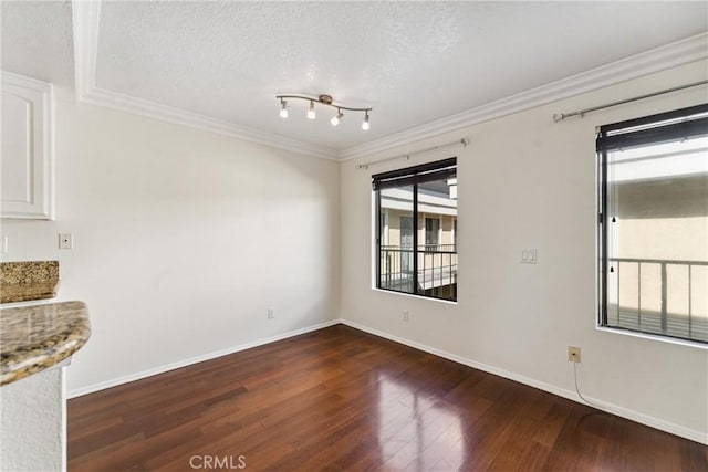 spare room featuring ornamental molding, a textured ceiling, and dark wood-type flooring