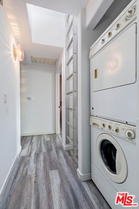 washroom featuring a skylight, hardwood / wood-style flooring, and stacked washer and clothes dryer