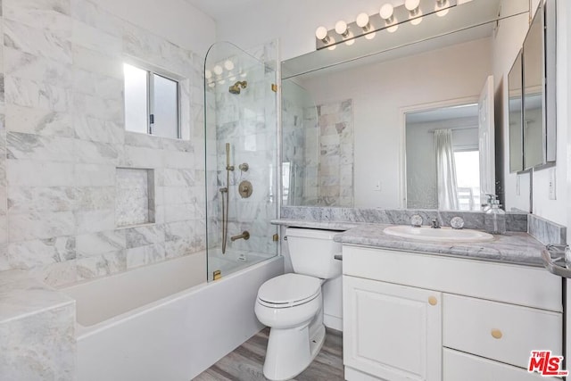 full bathroom with wood-type flooring, tiled shower / bath, vanity, and toilet