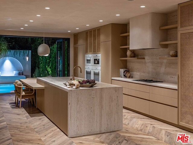 kitchen featuring an island with sink, hanging light fixtures, gas cooktop, white double oven, and light parquet floors