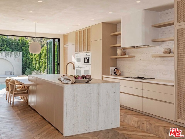 kitchen with hanging light fixtures, gas cooktop, white double oven, backsplash, and a center island with sink