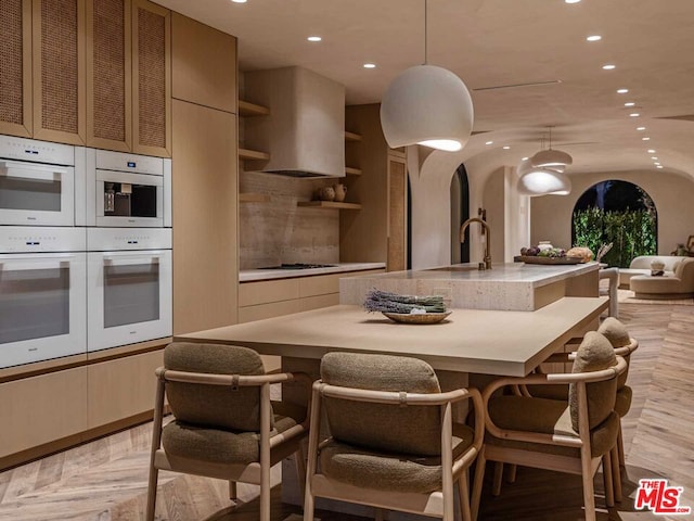 kitchen with pendant lighting, light parquet floors, cooktop, and white double oven