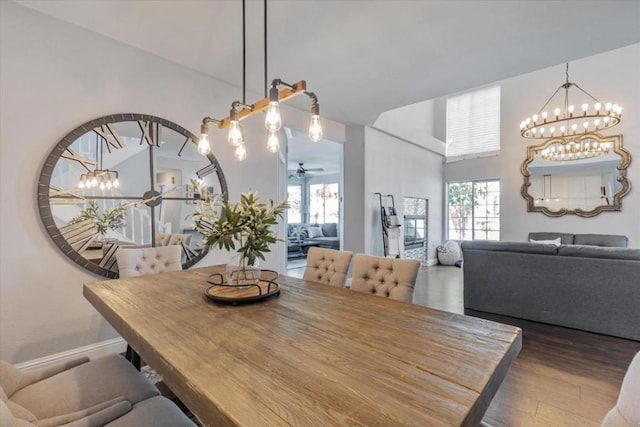 dining room with dark hardwood / wood-style floors and ceiling fan with notable chandelier