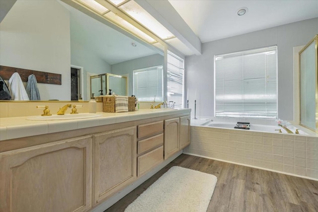 bathroom featuring wood-type flooring, shower with separate bathtub, vaulted ceiling, and vanity