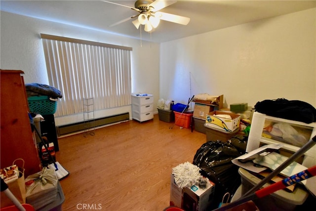 miscellaneous room with a baseboard radiator, wood-type flooring, and ceiling fan