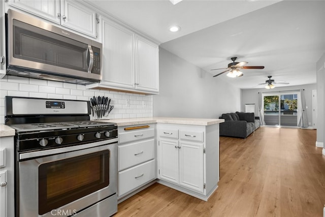 kitchen featuring tasteful backsplash, white cabinets, stainless steel appliances, and light hardwood / wood-style floors