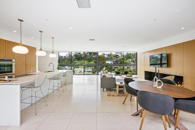 dining room featuring light tile patterned flooring, wood walls, sink, and expansive windows