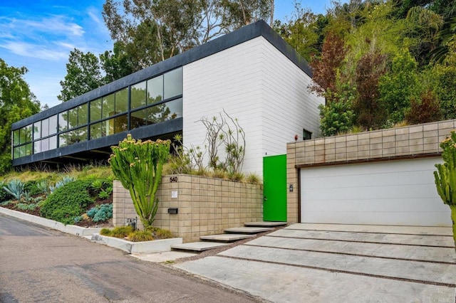 contemporary home featuring driveway, an outdoor structure, and a garage