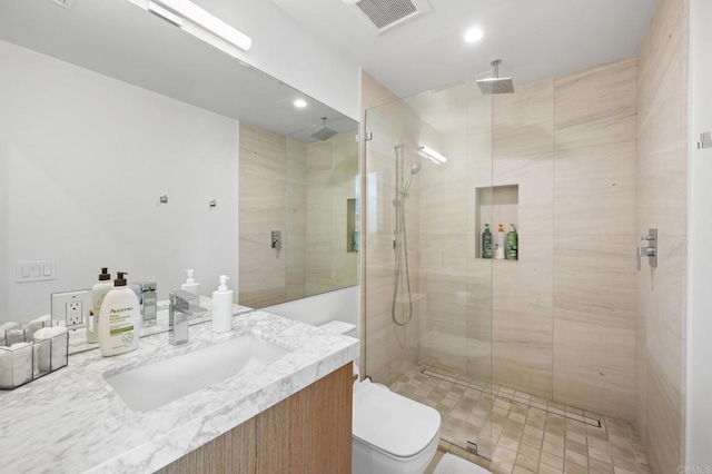 bathroom with a shower with shower door, vanity, and toilet