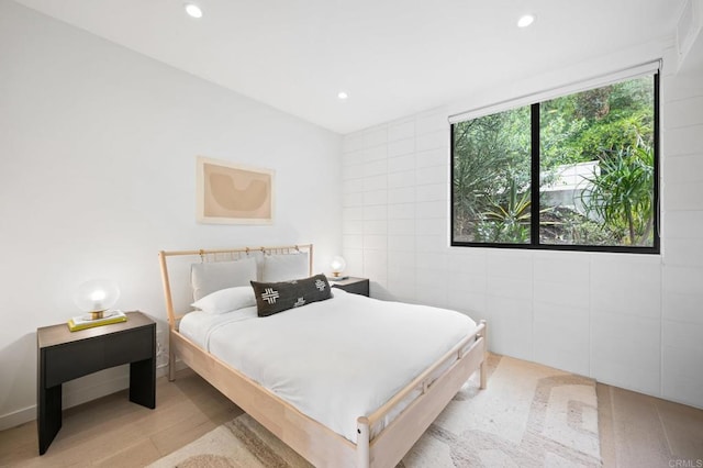 bedroom with light hardwood / wood-style flooring and tile walls