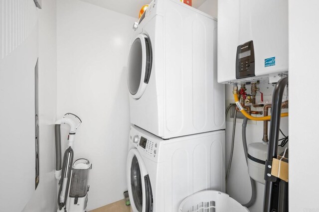 clothes washing area with stacked washer / dryer and water heater