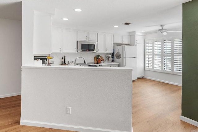 kitchen featuring white cabinets, white refrigerator, kitchen peninsula, and tasteful backsplash