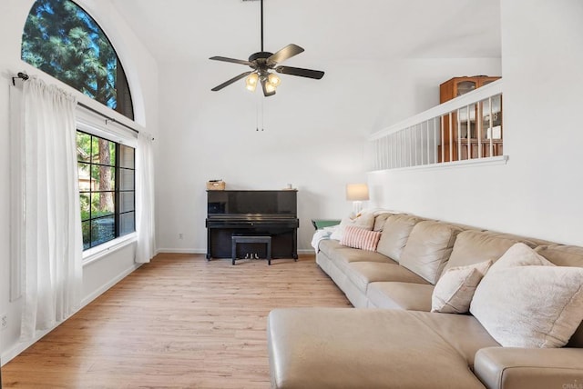 living room featuring ceiling fan, light hardwood / wood-style floors, and a high ceiling