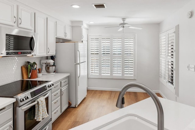 kitchen with white cabinetry, ceiling fan, sink, stainless steel appliances, and light hardwood / wood-style flooring