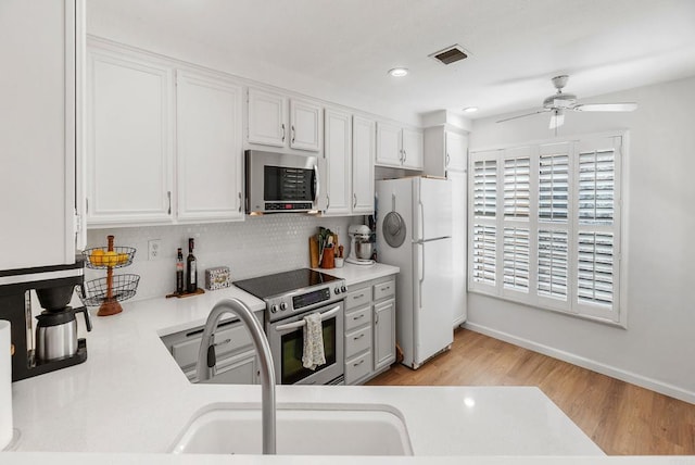 kitchen with white cabinets, light wood-type flooring, and appliances with stainless steel finishes