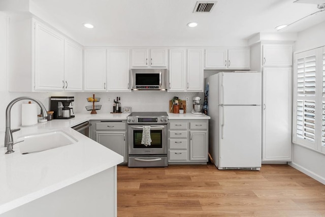 kitchen featuring sink, a healthy amount of sunlight, light hardwood / wood-style flooring, white cabinets, and appliances with stainless steel finishes