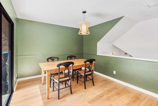 dining space featuring light hardwood / wood-style floors and vaulted ceiling