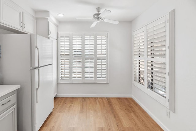 kitchen with white cabinets, ceiling fan, white refrigerator, and light hardwood / wood-style flooring