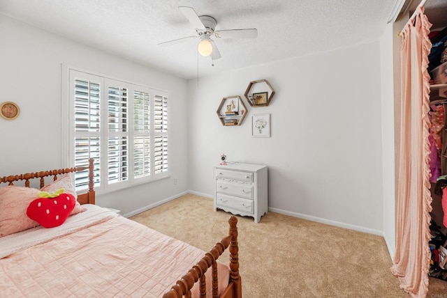 bedroom featuring ceiling fan, light colored carpet, and a textured ceiling