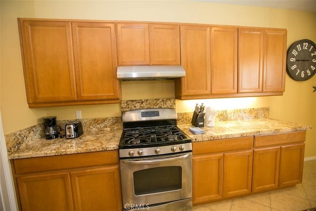 kitchen featuring light tile patterned floors, gas range, and light stone countertops