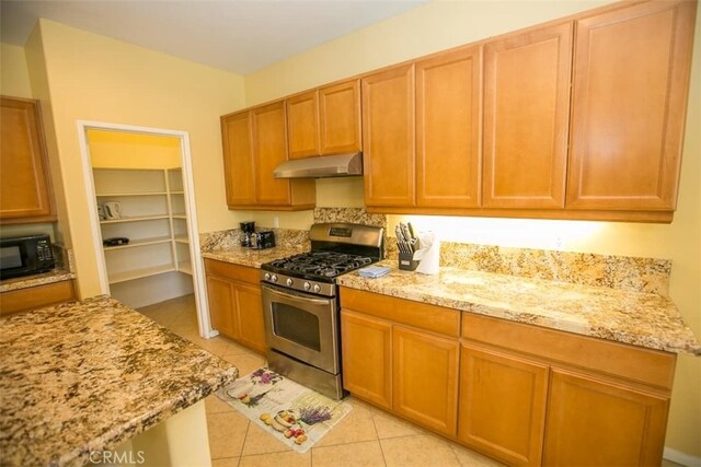 kitchen featuring light stone counters, light tile patterned floors, and stainless steel range with gas cooktop