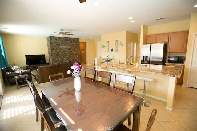 tiled dining room featuring ceiling fan and sink