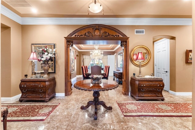 foyer entrance with ornamental molding and a chandelier