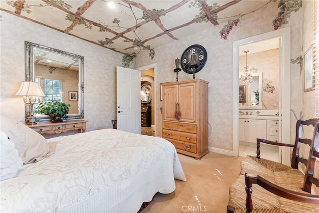 bedroom featuring connected bathroom, a chandelier, and light colored carpet