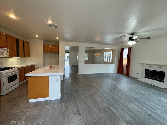 kitchen featuring dark hardwood / wood-style flooring, a textured ceiling, white appliances, a kitchen island, and ceiling fan with notable chandelier