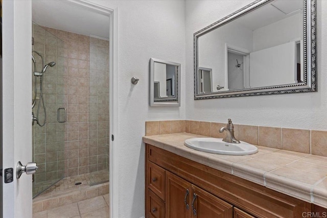 bathroom featuring tile patterned flooring, an enclosed shower, and vanity