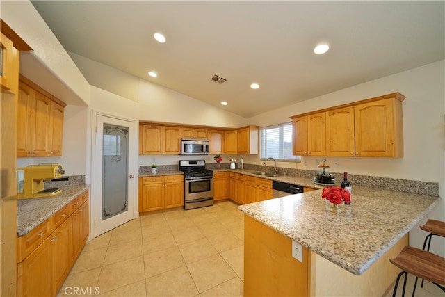 kitchen featuring light stone countertops, sink, kitchen peninsula, lofted ceiling, and appliances with stainless steel finishes