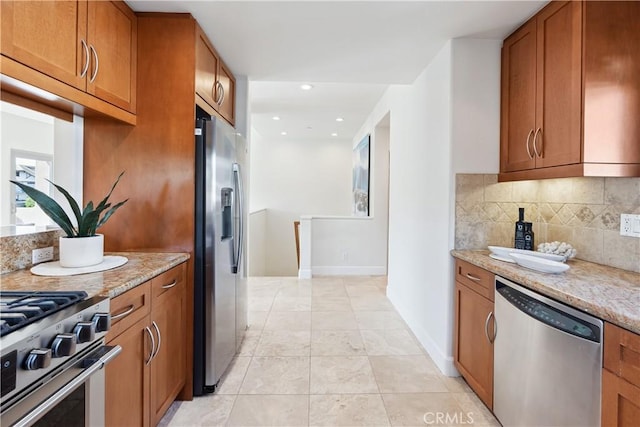 kitchen with backsplash, light stone countertops, and appliances with stainless steel finishes