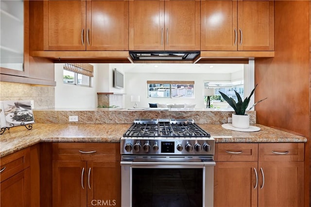 kitchen with decorative backsplash, light stone countertops, and high end range