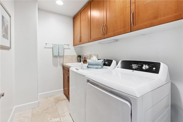 laundry room featuring washing machine and dryer, light tile patterned flooring, and cabinets