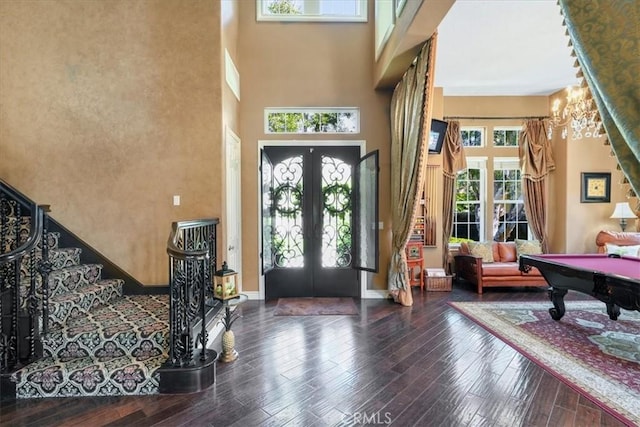 foyer featuring billiards, french doors, a towering ceiling, and hardwood / wood-style flooring