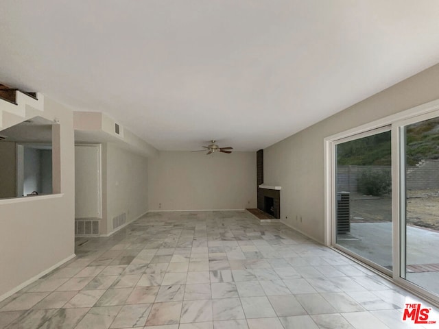 unfurnished living room with ceiling fan and a large fireplace