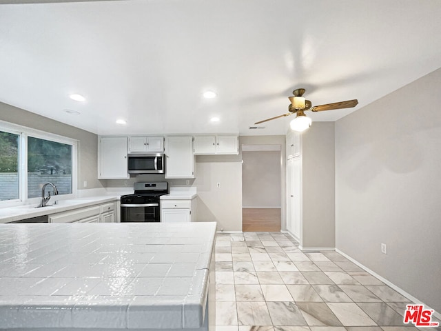 kitchen with sink, tile counters, white cabinets, and appliances with stainless steel finishes