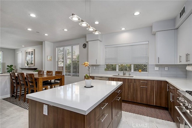 kitchen featuring a healthy amount of sunlight, white cabinetry, a kitchen island, and sink