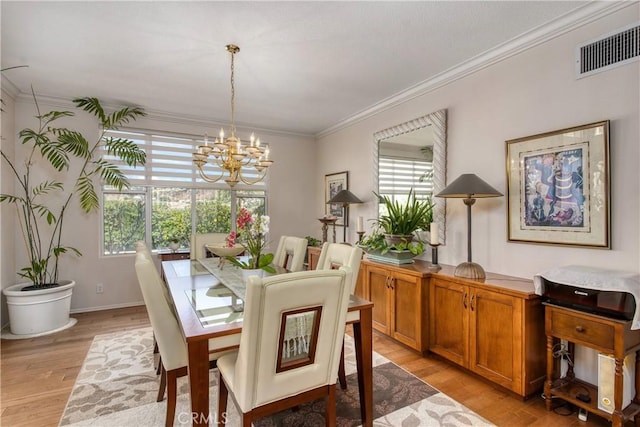 dining area with light wood-type flooring, crown molding, and a notable chandelier