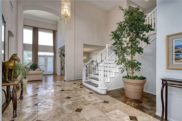 foyer featuring a notable chandelier, ornamental molding, and a high ceiling