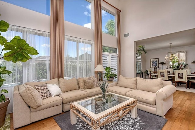 living room featuring light hardwood / wood-style flooring, a chandelier, and a high ceiling